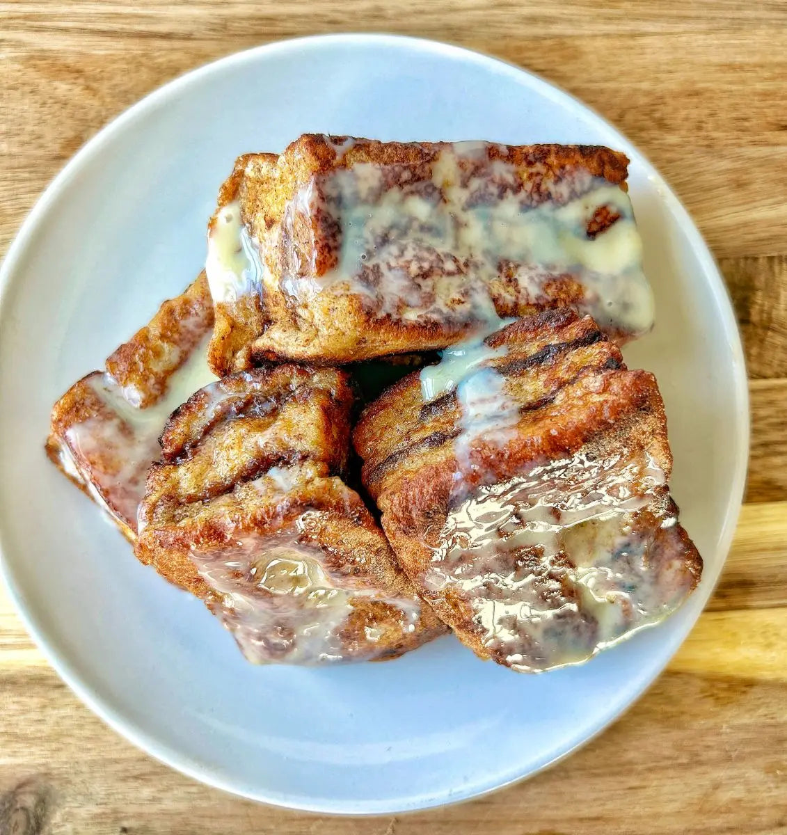 Nutella stuffed brioche French toast stacked on a plate drizzled with sweetened condensed milk