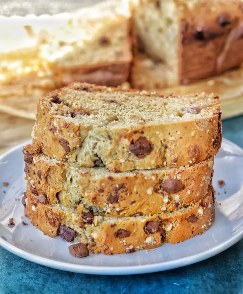 Chocolate banana nut bread loaf with melted chocolate chunks and mixed nuts, sliced and served on a wooden board